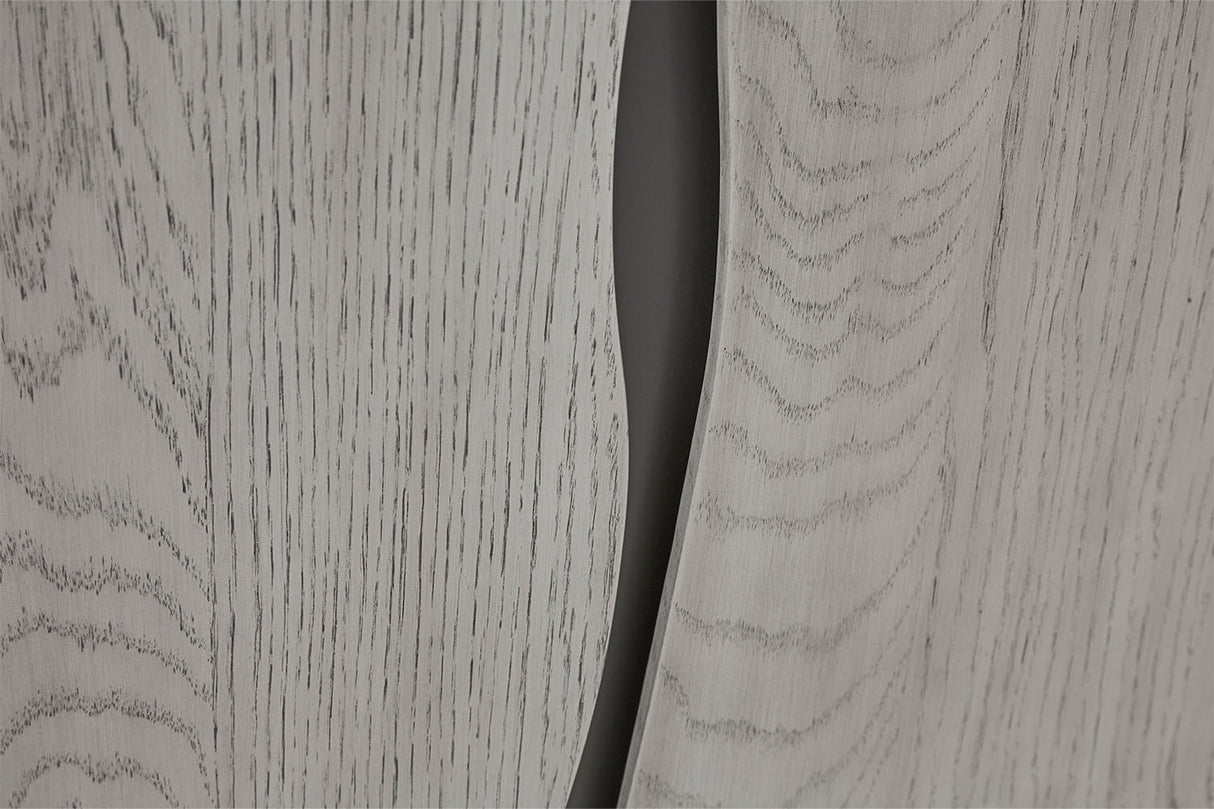 Close-up of a light gray woodgrain surface with a dark curved slit or gap running vertically through the center.