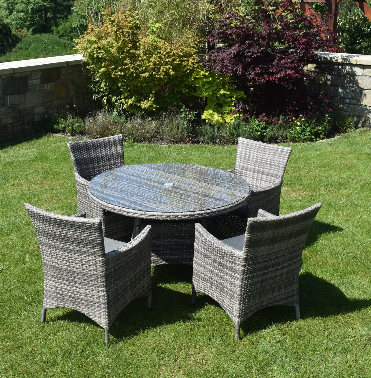 Round outdoor table with four matching chairs on a grassy area