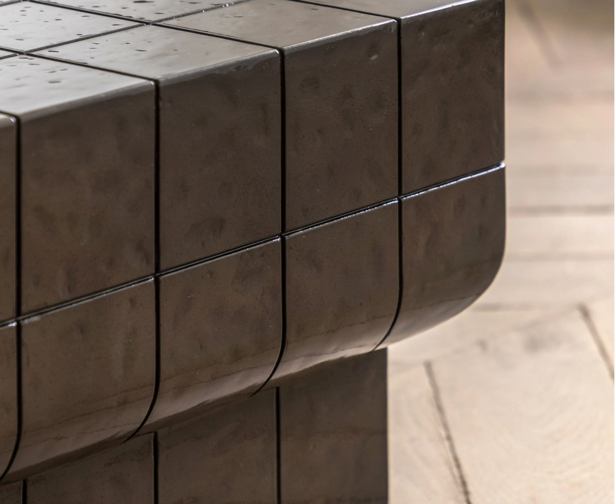 Novara contemporary coffee table crafted from charcoal brown glazed glass concrete, showcasing its sleek low-profile and retro faux tile surface detail at the furniture store ni