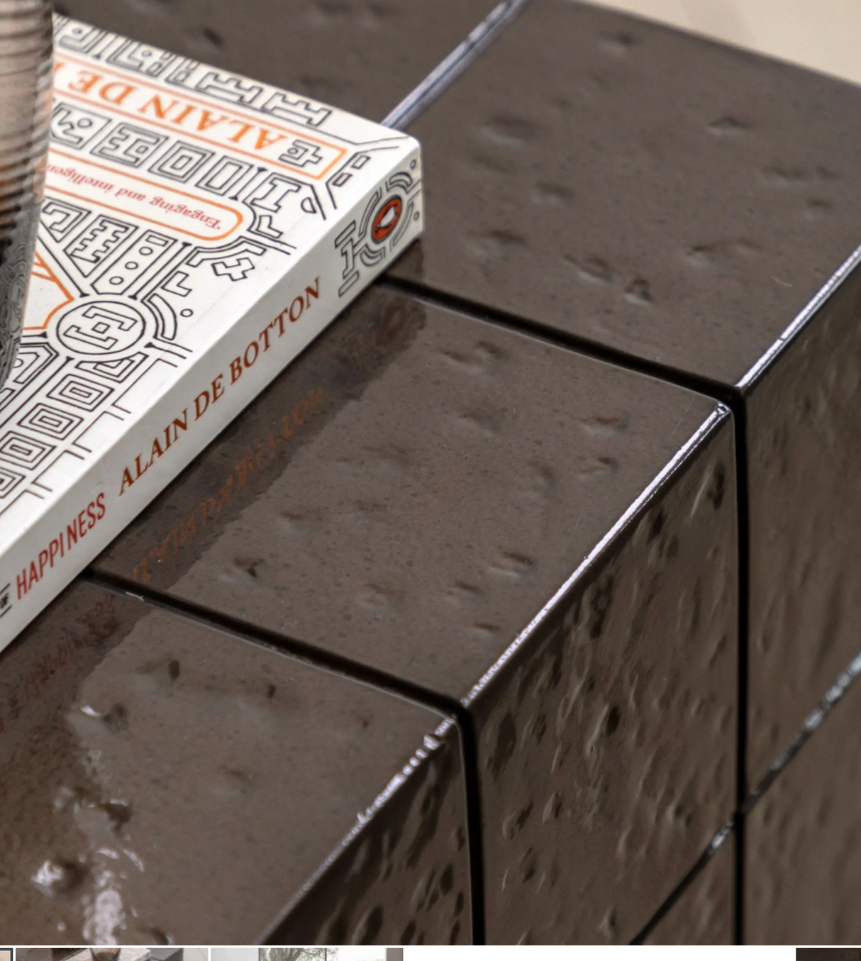 close up of Novara contemporary side table crafted from charcoal brown glazed glass concrete, showcasing its compact block profile and retro faux tile surface pattern at the furniture store ni