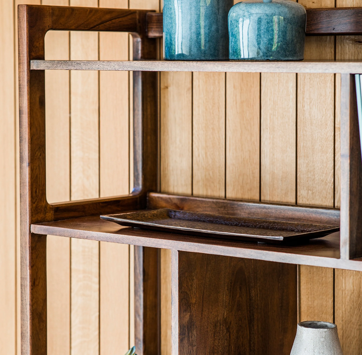 Wooden shelf with a laptop and decorative items against a wooden wall.