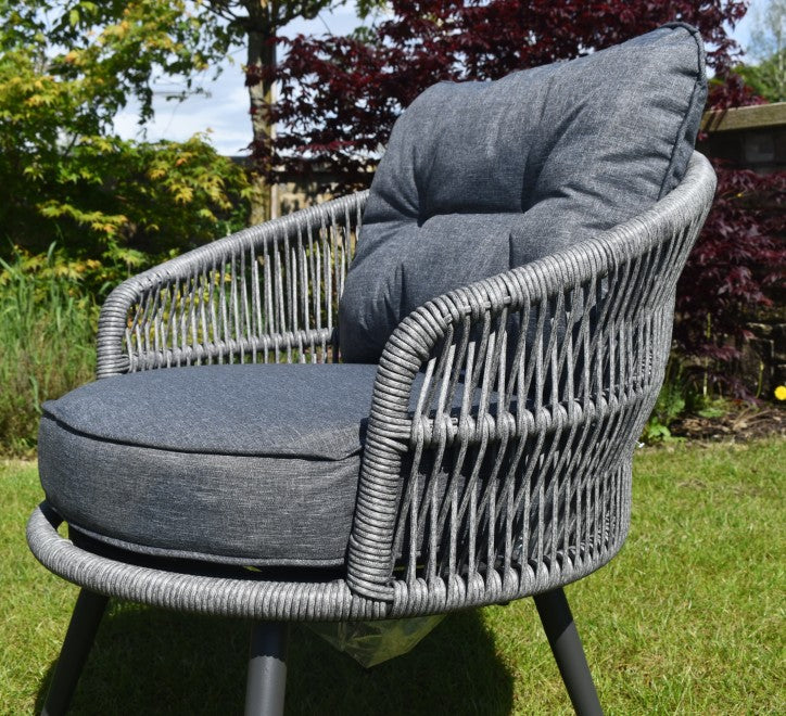 Gray wicker chair with dark cushions in a garden setting furniture store ni