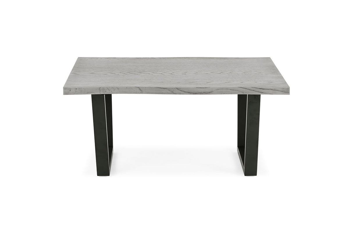 A modern rectangular table with a light gray stone or concrete-look top and two black angled legs, shown on a plain white background.