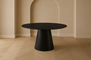 Black round table in a room with beige walls and wooden floor at the furniture store ni