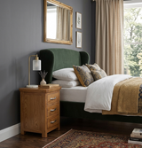 Bedroom with manhattan oak nightstand, green wingback bed, and decorative elements at furniture store ni