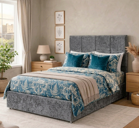 Bedroom with Prime grey upholstered bed, blue and white floral bedding, and wooden nightstands at furniture store ni