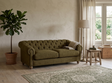 Modern 3-seater Chesterfield sofa showcasing its deep-buttoned back, elegant scrolled arms, and gracefully contoured silhouette sitting on solid ash legs at the furniture store ni