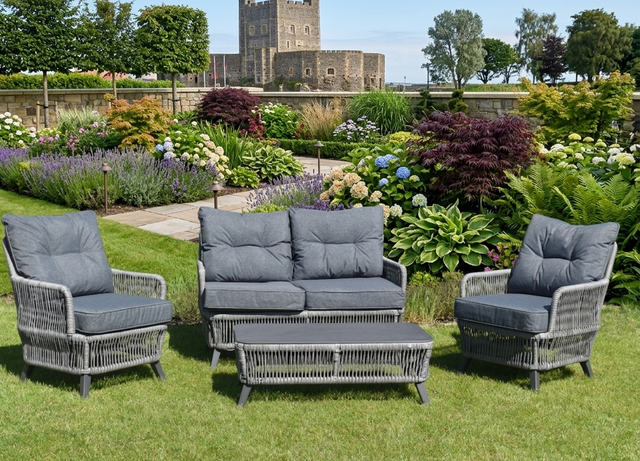 Rivera 4-piece garden furniture set including two rattan armchairs, a two-seater sofa, and a coffee table on a patio at the furniture store ni