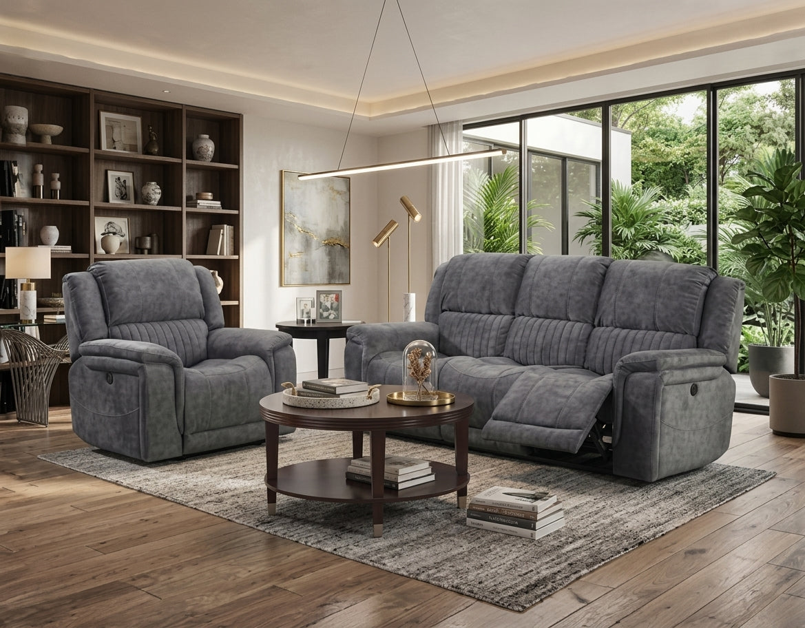 A modern living room setup featuring a gray upholstered reclining sofa and matching recliner chair, styled with a round wooden coffee table and a textured area rug on a hardwood floor.