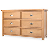 Newbury 6-drawer wide chest in light oak with distinctive drawer beading and polished silver cup handles at the furniture store ni