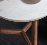 Round marble table with wooden legs on a dark background
