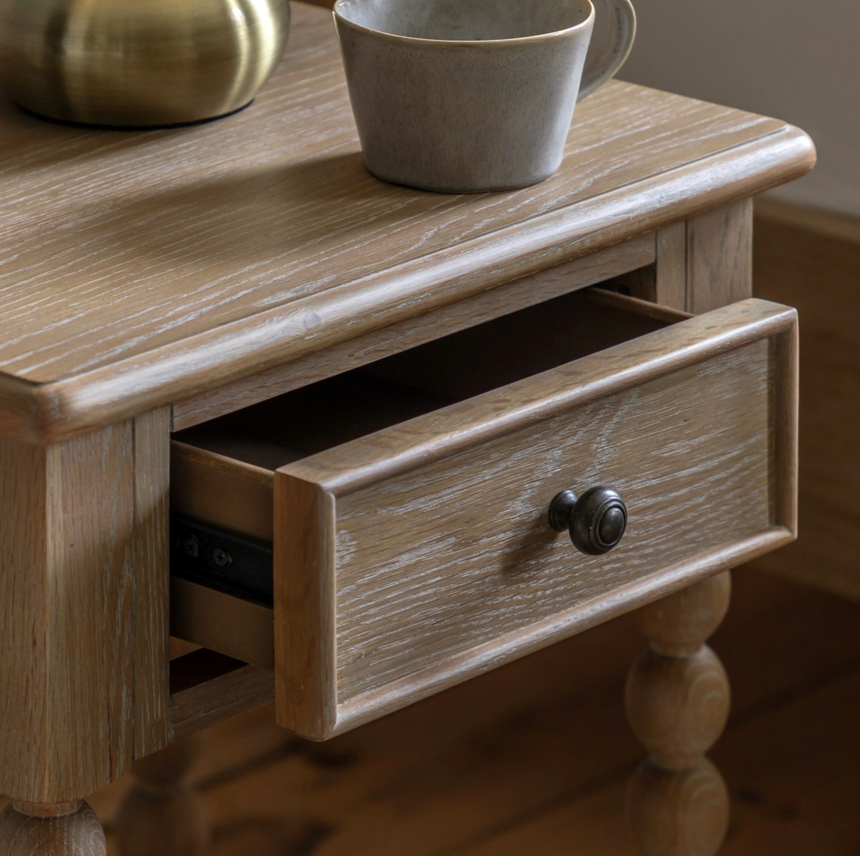 Wooden side table with a drawer and a cup on top at the furniture store ni
