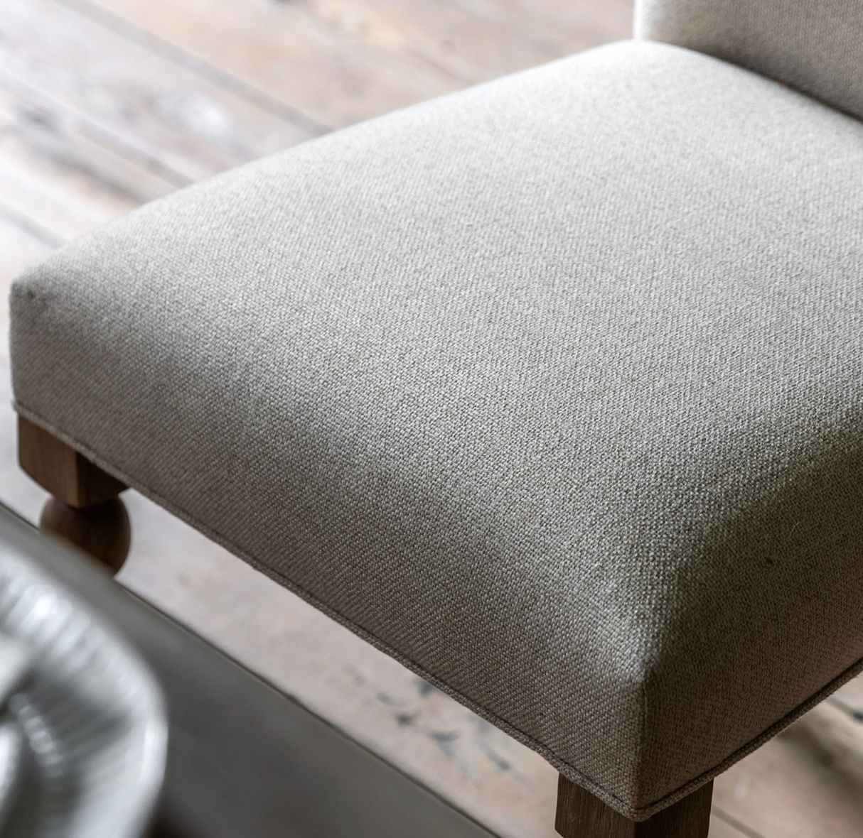 Close-up of a textured gray chair cushion on a wooden chair.