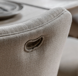 Close-up of a textured beige fabric surface with a small embroidered design.