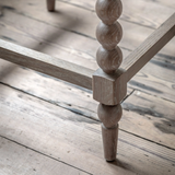 Wooden table leg with spiral design on a wooden floor