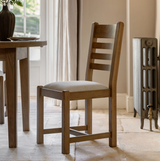 Pair of Hardwick dining chairs showcasing their warm natural oak wood grain finish, classic slatted back design, and plush neutral cushioned seats at the furniture store ni