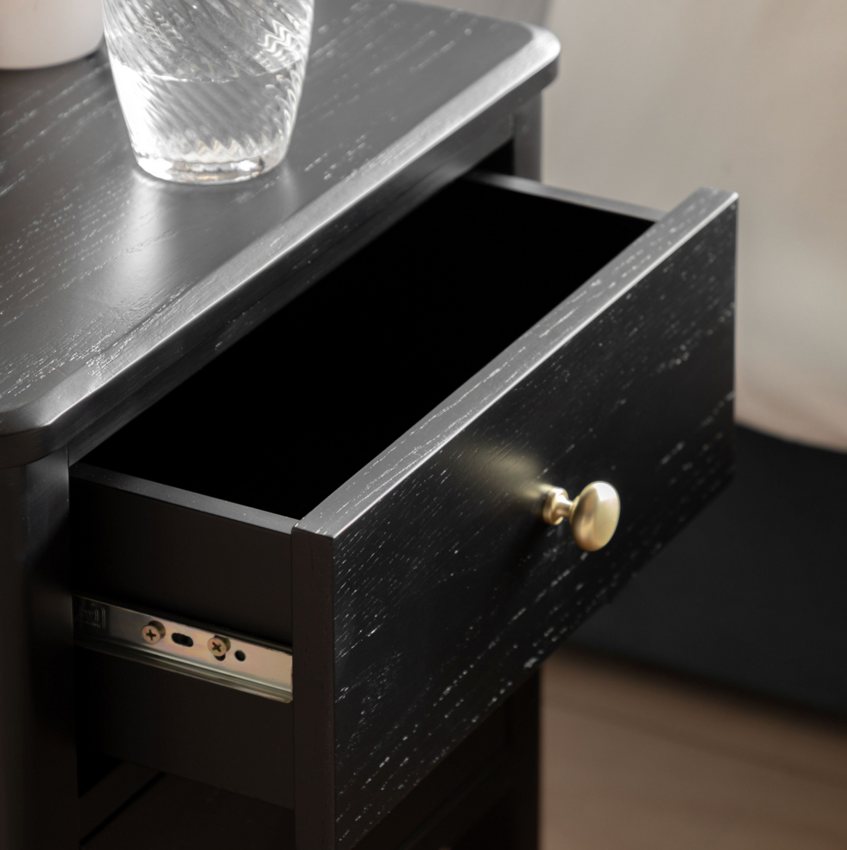 Black drawer with a gold handle on a wooden surface.