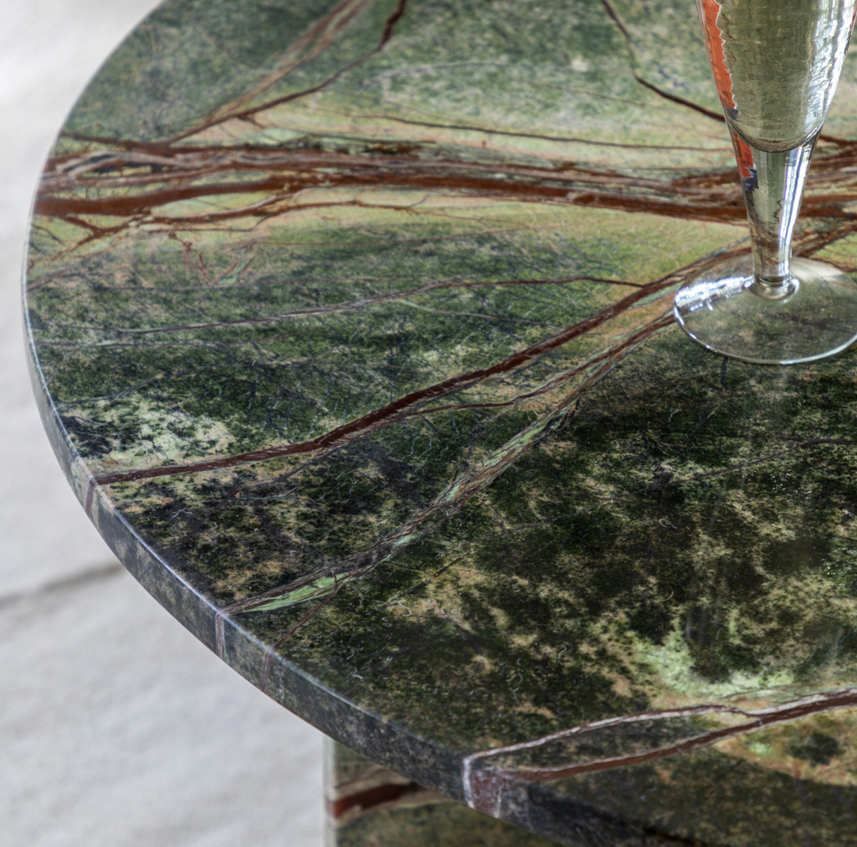Green marble table with a glass of champagne on a white background