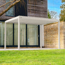 Nova Titan pergola in a Pebble finish featuring adjustable louvres, set in a modern garden patio with natural wood and stone materials. furniture store ni