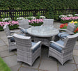 Majorca 6-seater garden dining set featuring a glass-top rattan table and six comfortable armchairs with grey cushions on a patio at furniture store ni