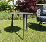 Gray outdoor table in a garden setting with a chair and greenery furniture store ni