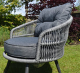 Gray wicker chair with dark cushions in a garden setting furniture store ni